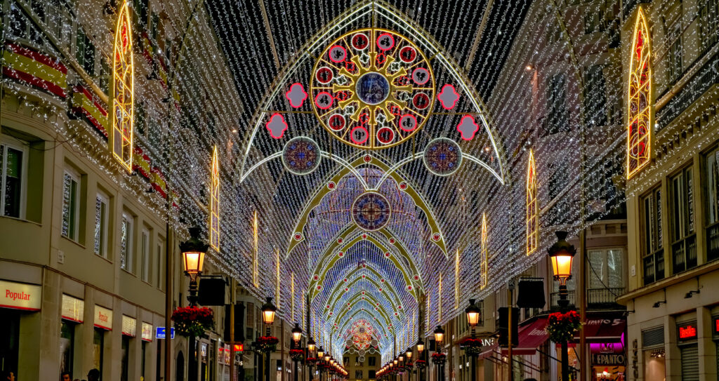 A festive street in Andalusia with bright Christmas lights, traditional Nativity scenes, and people enjoying holiday celebrations. Malaga, Spain