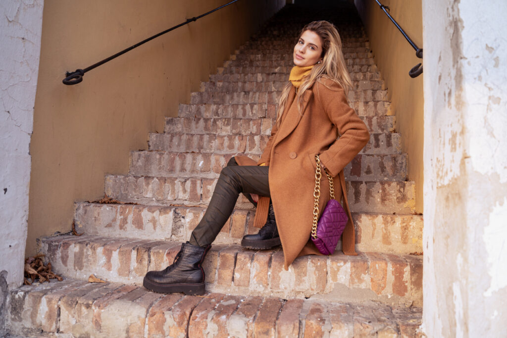 Blonde with long hair in fall fashion style sitting on stairs and posing