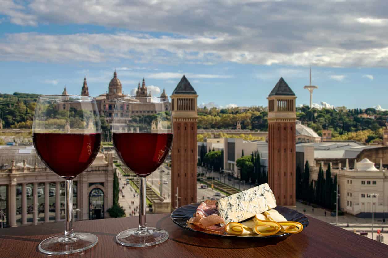 Two glasses of wine with meat and cheese snacks against Spain square in Barcelona, Spain