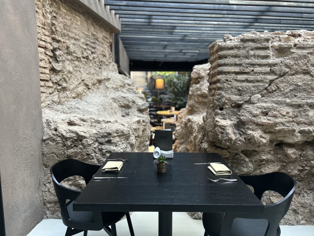 Breakfast table at Caro Hotel’s dining room set with fresh pastries, coffee, and fruit, beside historic stone walls